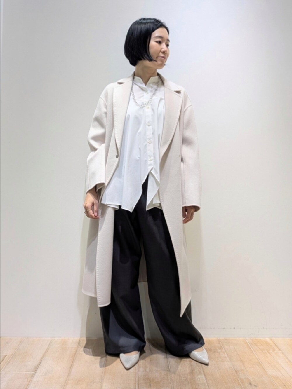 ベージュ系のチェスターコート、ホワイト系のシャツ/ブラウス、グレー系のその他パンツを着用したレディースの秋コーディネートの4枚目の写真