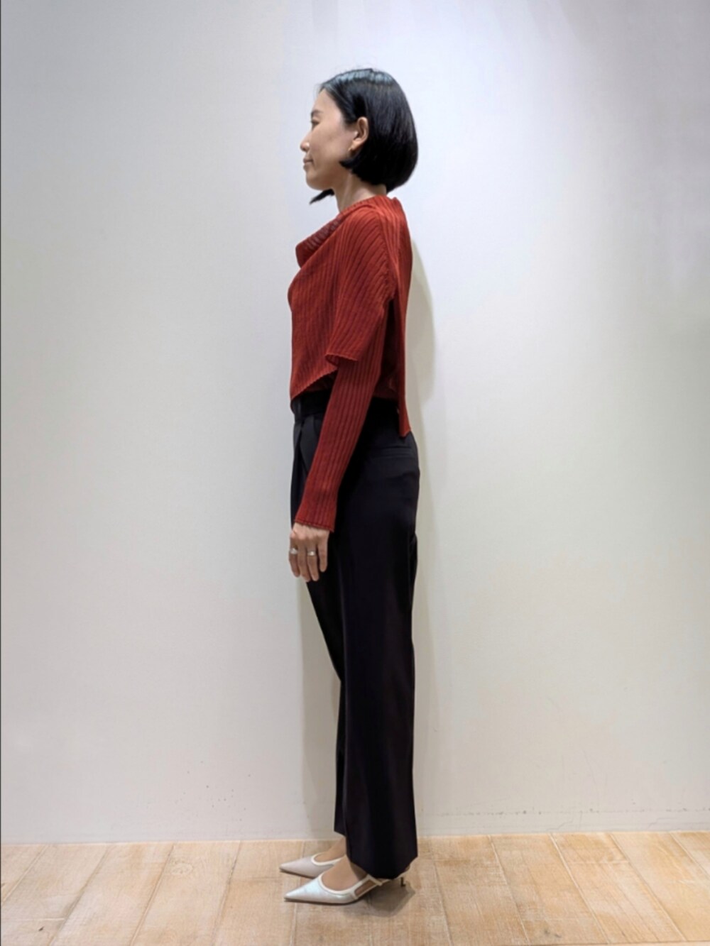 オレンジ系のニット/セーター、ブルー系のスラックスを着用したレディースの秋コーディネートの4枚目の写真