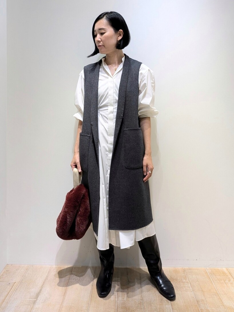 ベージュ系のベスト、ホワイト系のワンピース、ブラウン系のトートバッグを着用したレディースの秋コーディネートの3枚目の写真