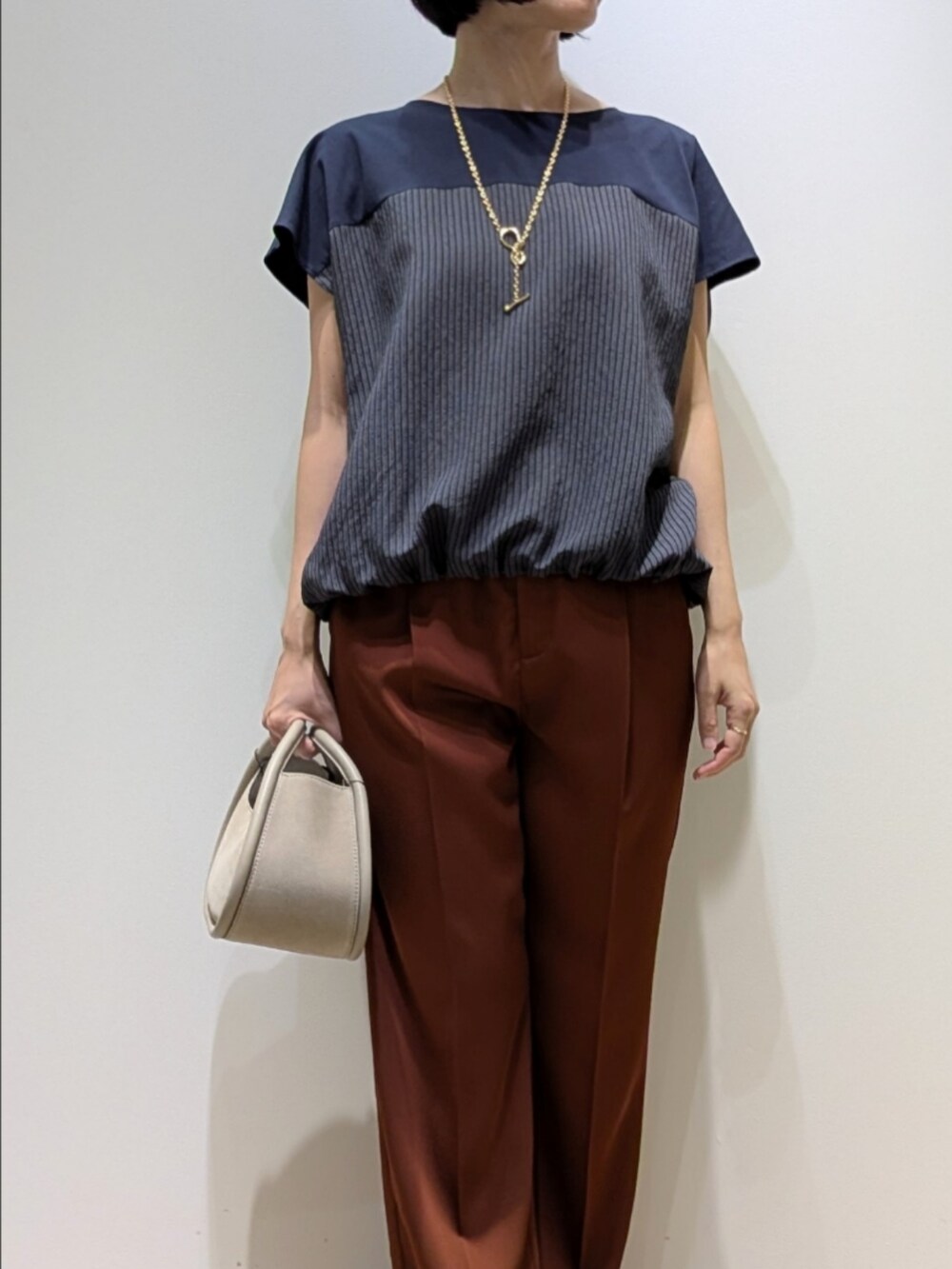 ブラウン系のその他パンツ、ブルー系のTシャツ/カットソー、ゴールド系のネックレスを着用したレディースの秋コーディネートの2枚目の写真