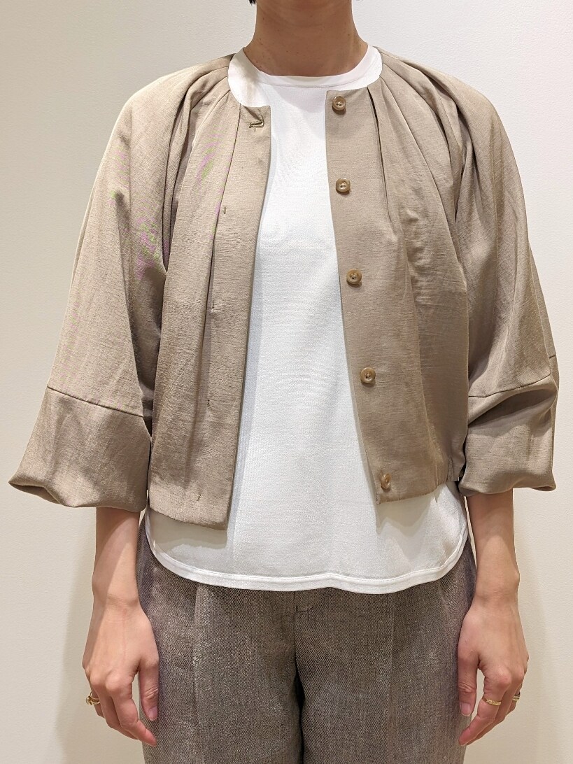 グリーン系のノーカラージャケット、ホワイト系のニット/セーター、グレー系のスラックスを着用したレディースの春コーディネートの2枚目の写真