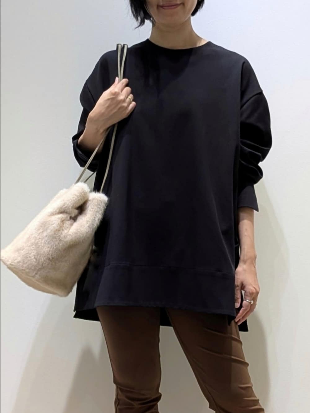 ブラック系のスウェット、ブラウン系のその他パンツ、ホワイト系のショルダーバッグを着用したレディースの秋コーディネートの2枚目の写真