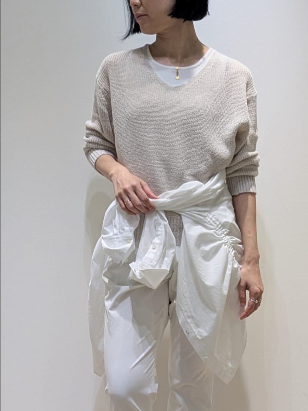 ベージュ系のニット/セーター、ホワイト系のその他パンツ、ホワイト系のシャツ/ブラウスを着用したレディースの春コーディネートの2枚目の写真