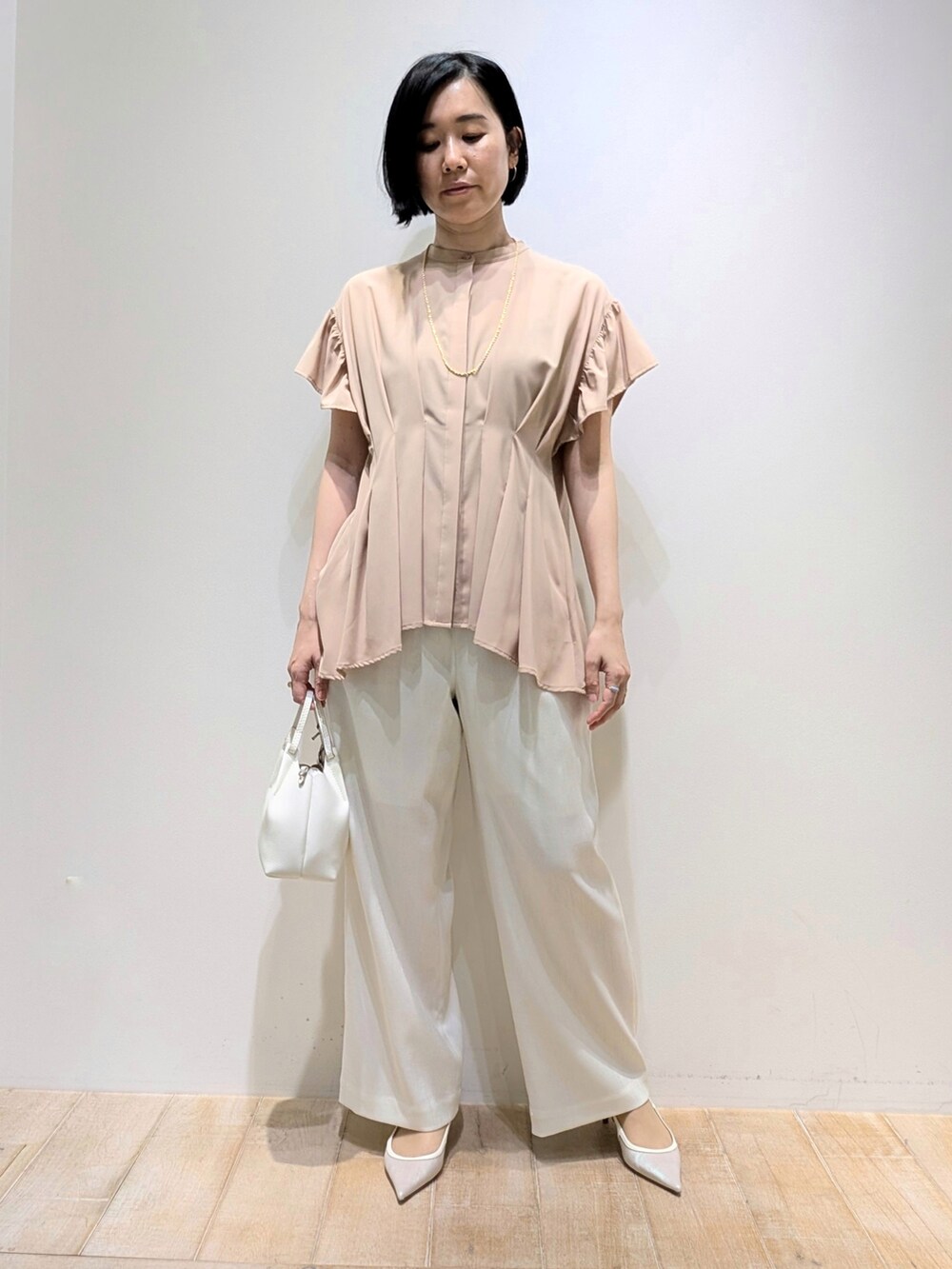 ホワイト系のスラックス、ベージュ系のシャツ/ブラウスを着用したレディースの夏コーディネートの2枚目の写真