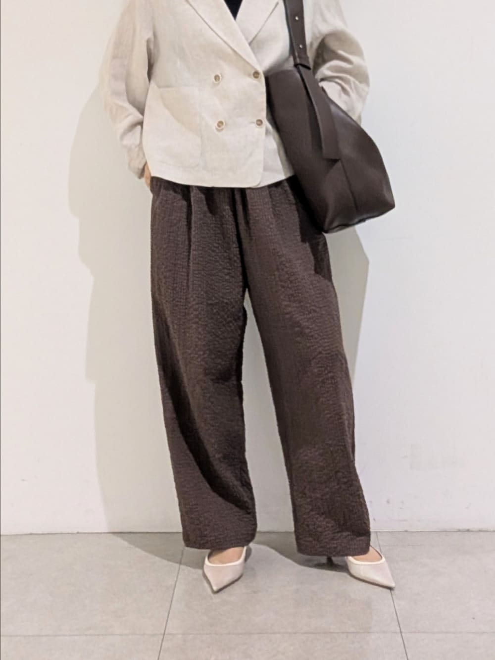 ベージュ系のテーラードジャケット、ブラウン系のその他パンツ、シルバー系のネックレスを着用したレディースの秋コーディネートの3枚目の写真