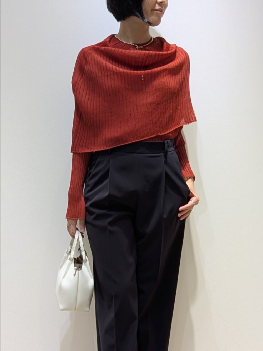 オレンジ系のニット/セーター、ブルー系のスラックスを着用したレディースの秋コーディネートの2枚目の写真