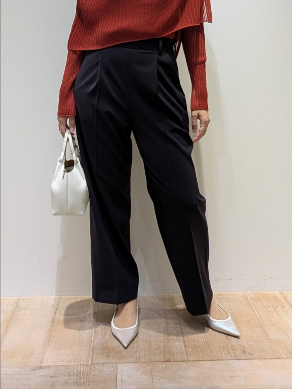 オレンジ系のニット/セーター、ブルー系のスラックスを着用したレディースの秋コーディネートの3枚目の写真