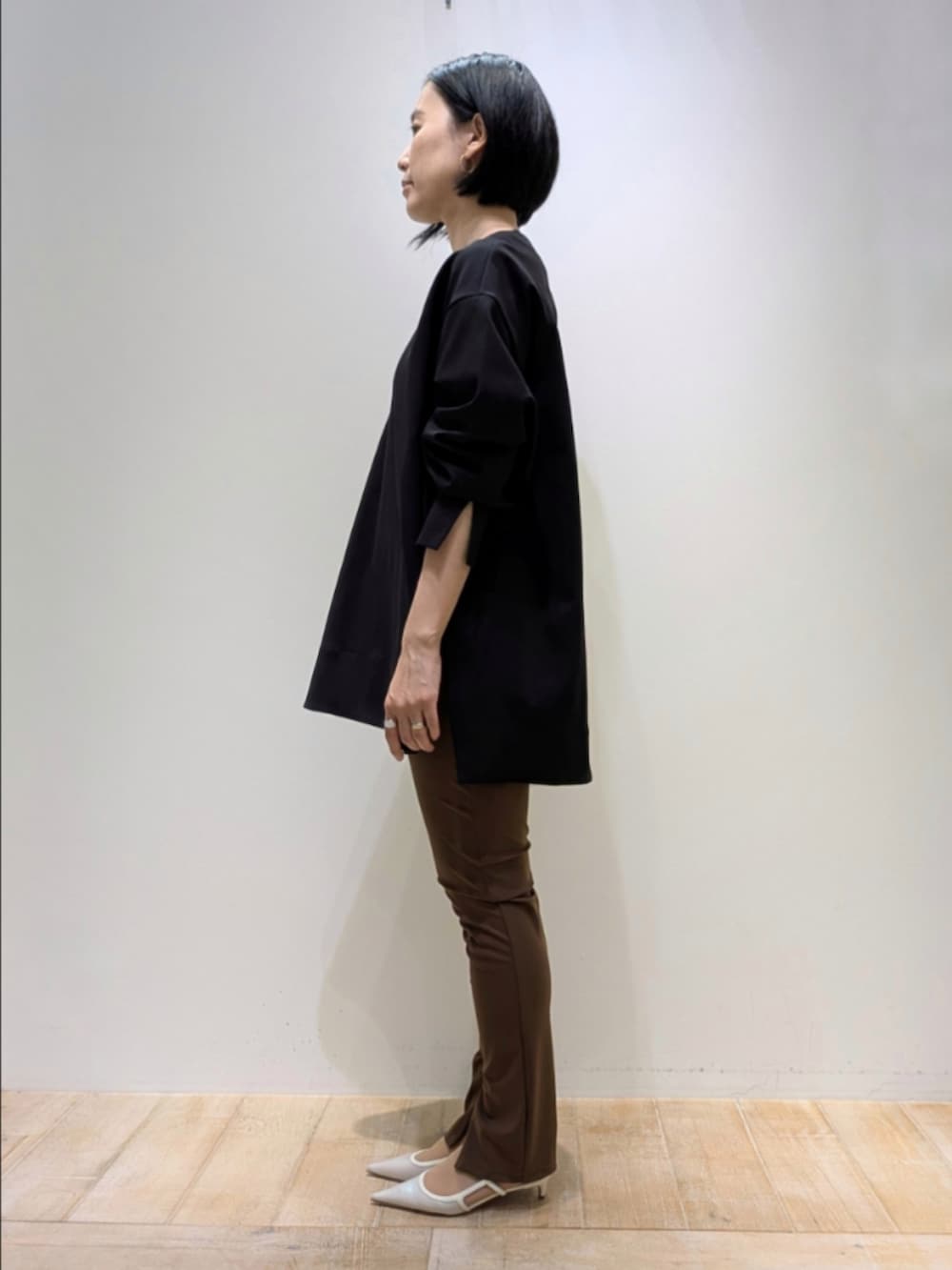 ブラック系のスウェット、ブラウン系のその他パンツ、ホワイト系のショルダーバッグを着用したレディースの秋コーディネートの4枚目の写真