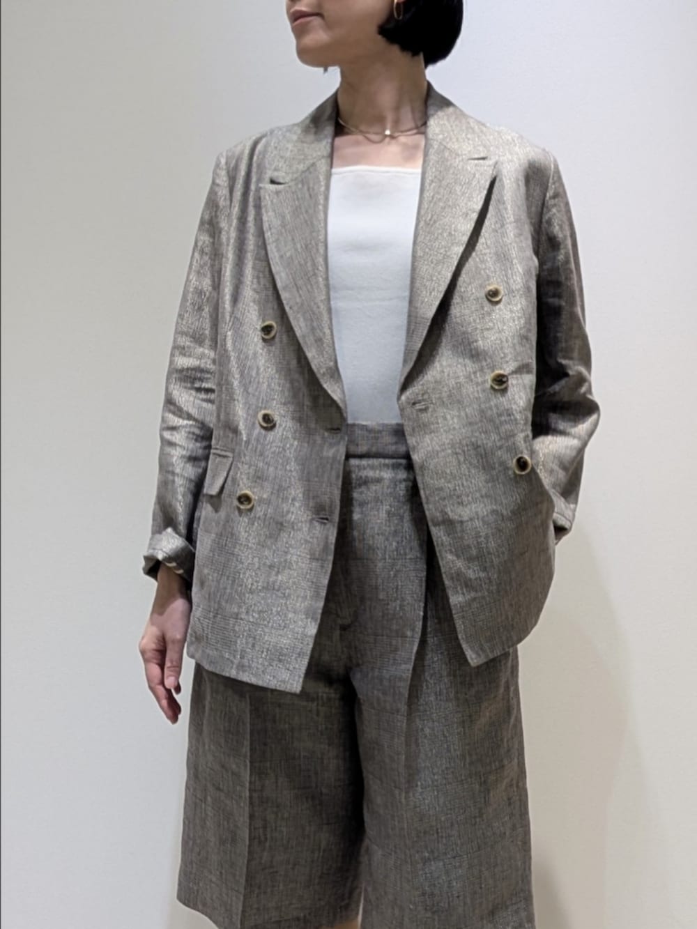 ベージュ系のテーラードジャケット、ベージュ系のその他パンツ、ホワイト系のタンクトップを着用したレディースの春コーディネートの2枚目の写真