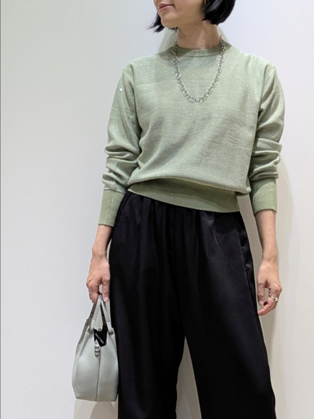 グリーン系のニット/セーター、ブラック系のその他パンツを着用したレディースの秋コーディネートの2枚目の写真