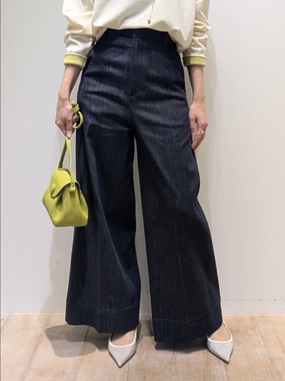 ホワイト系のニット/セーター、ブルー系のデニムパンツ、グリーン系のショルダーバッグを着用したレディースの冬コーディネートの3枚目の写真