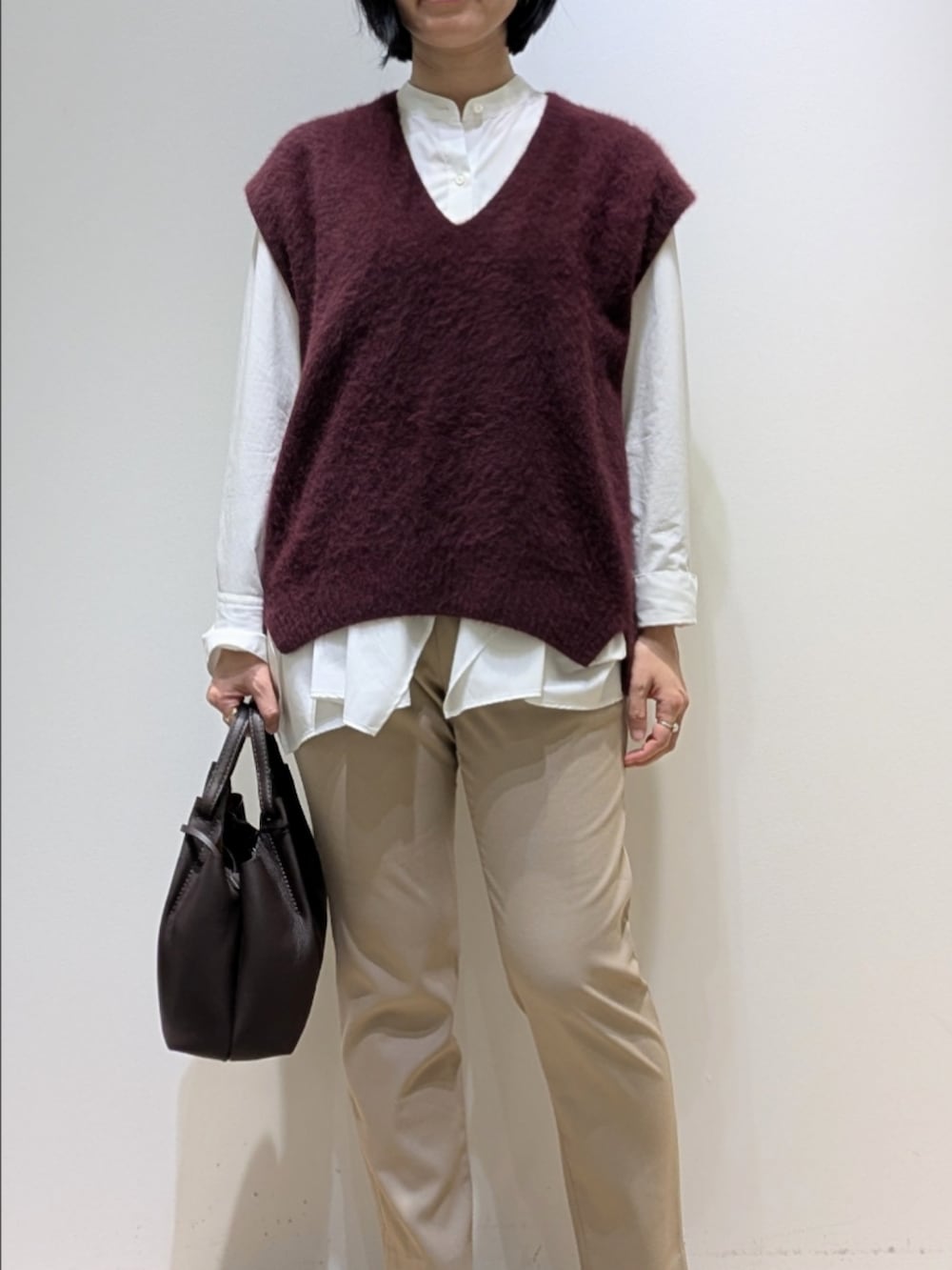 レッド系のベスト、ホワイト系のシャツ/ブラウス、ベージュ系のその他パンツを着用したレディースの秋コーディネートの2枚目の写真