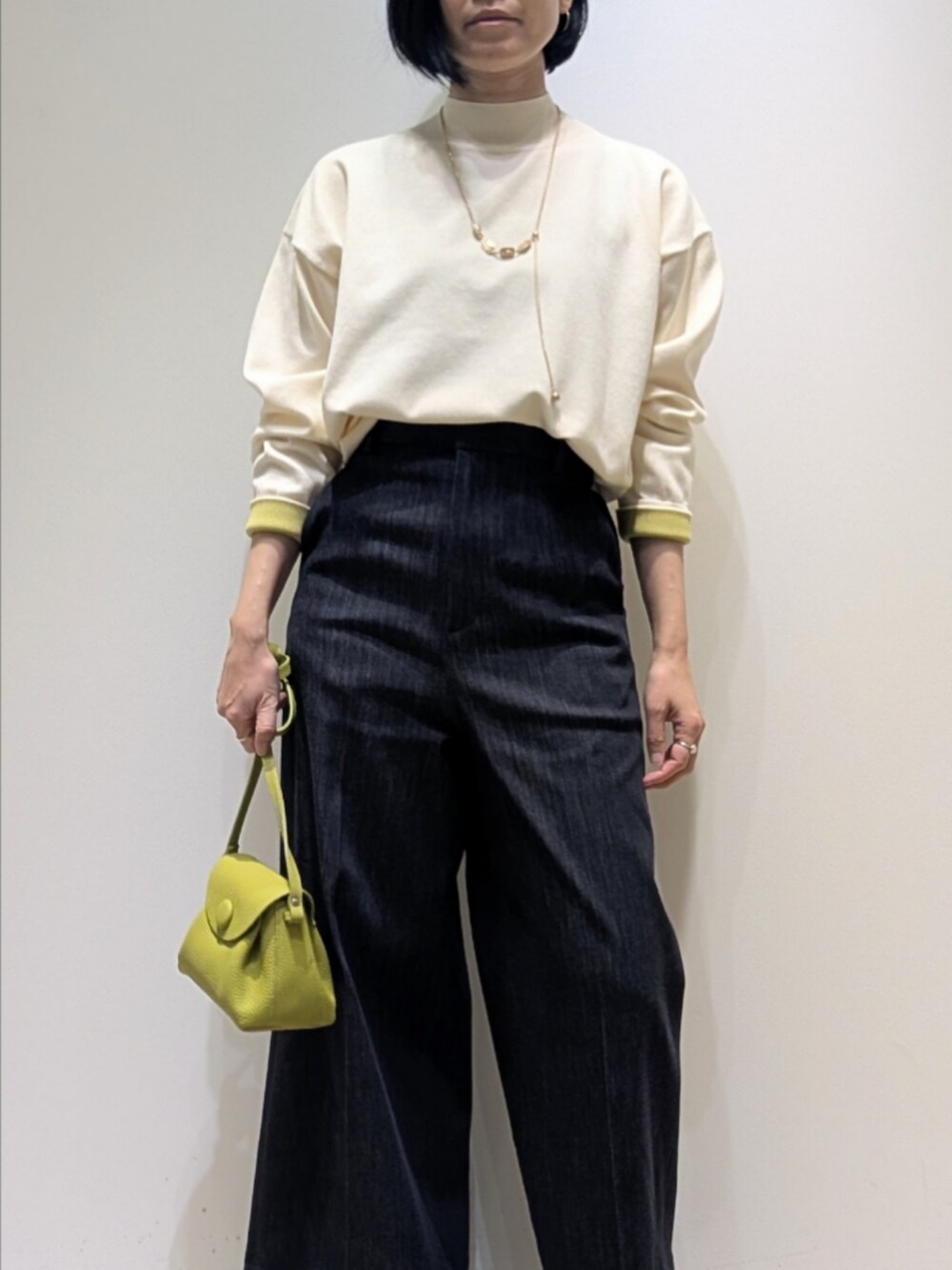 ホワイト系のニット/セーター、ブルー系のデニムパンツ、グリーン系のショルダーバッグを着用したレディースの冬コーディネートの2枚目の写真