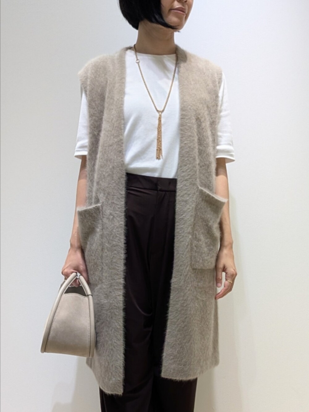 ホワイト系のTシャツ/カットソー、ブラウン系のベスト、ブラウン系のその他パンツを着用したレディースの秋コーディネートの2枚目の写真