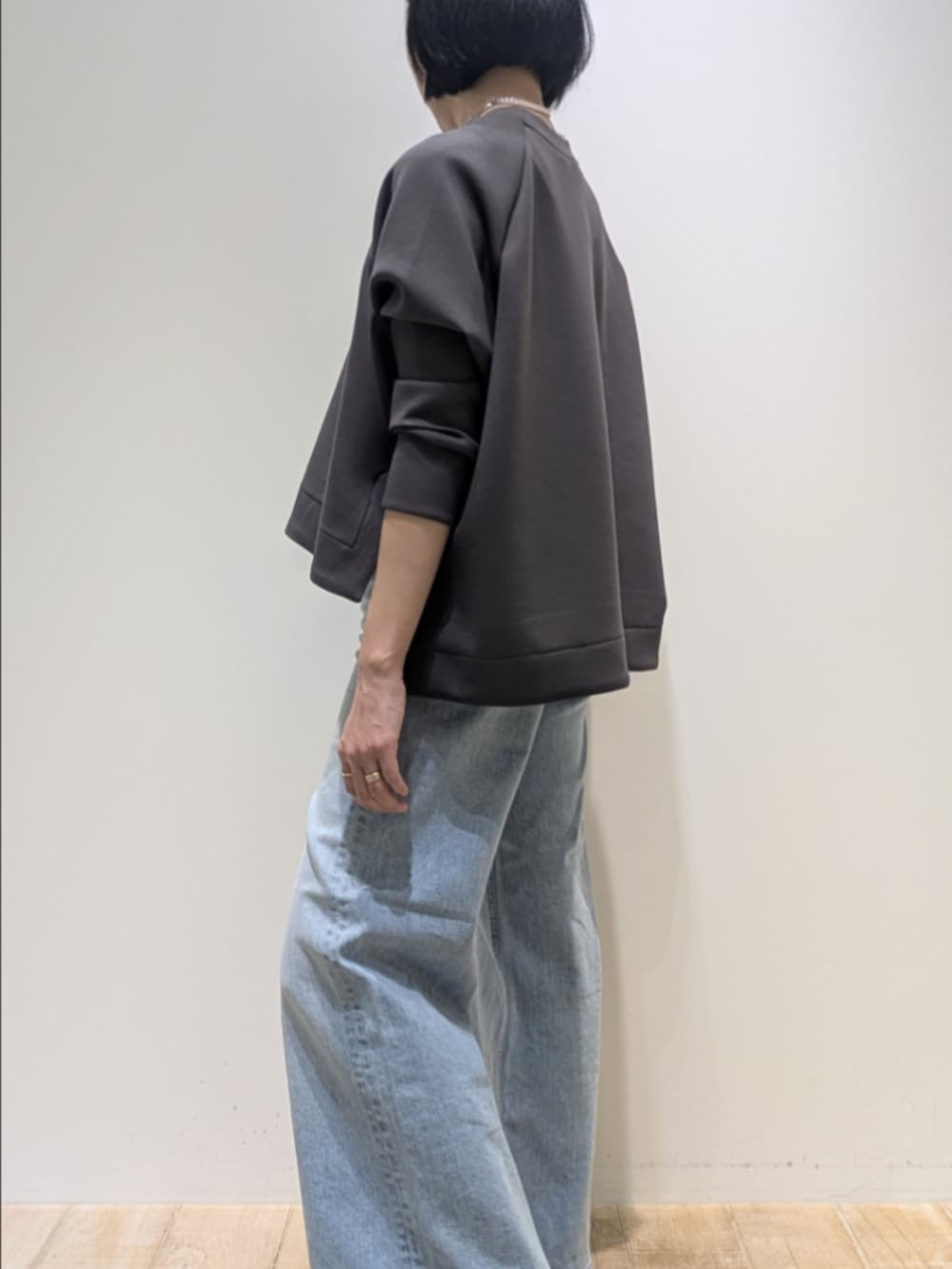 グレー系のスウェット、ブルー系のデニムパンツ、シルバー系のネックレスを着用したレディースの冬コーディネートの4枚目の写真