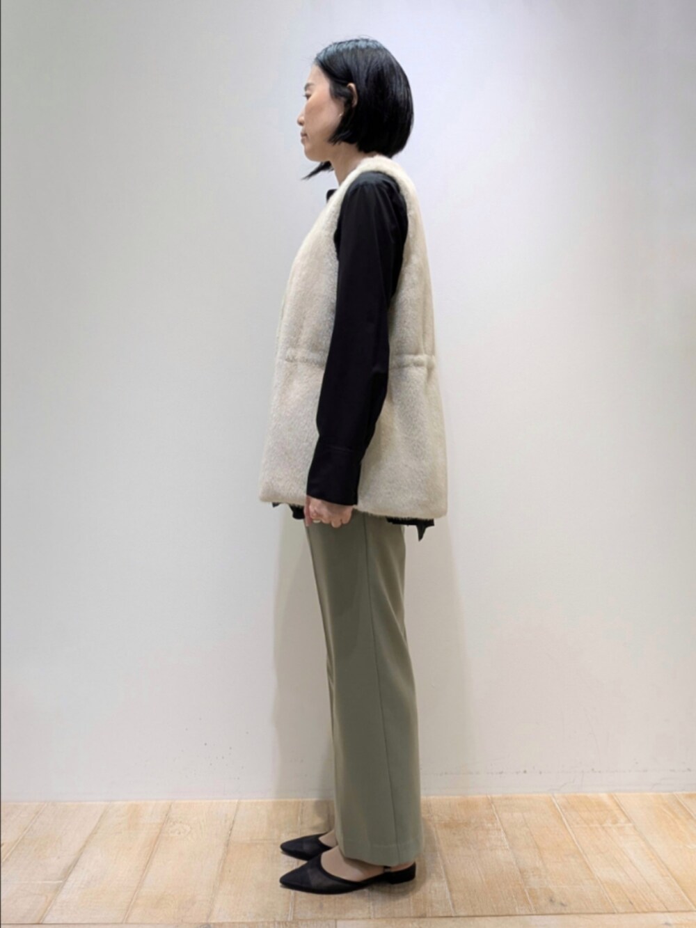 ブラック系のシャツ/ブラウス、ホワイト系のベスト、グリーン系のその他パンツを着用したレディースの秋コーディネートの4枚目の写真