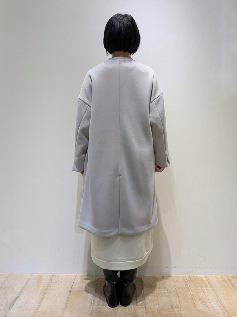 グレー系のノーカラーコート、ホワイト系のワンピースを着用したレディースの冬コーディネートの3枚目の写真