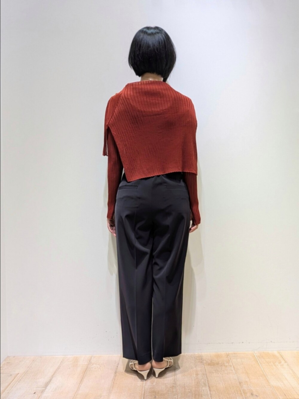 オレンジ系のニット/セーター、ブルー系のスラックスを着用したレディースの秋コーディネートの5枚目の写真