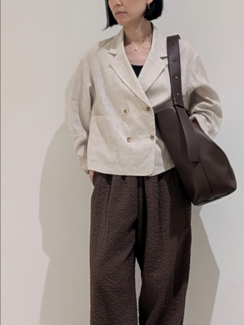 ベージュ系のテーラードジャケット、ブラウン系のその他パンツ、シルバー系のネックレスを着用したレディースの秋コーディネートの2枚目の写真