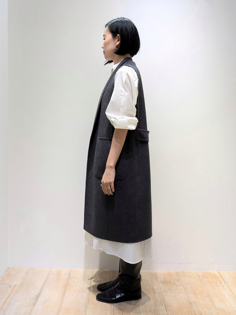 ベージュ系のベスト、ホワイト系のワンピース、ブラウン系のトートバッグを着用したレディースの秋コーディネートの2枚目の写真