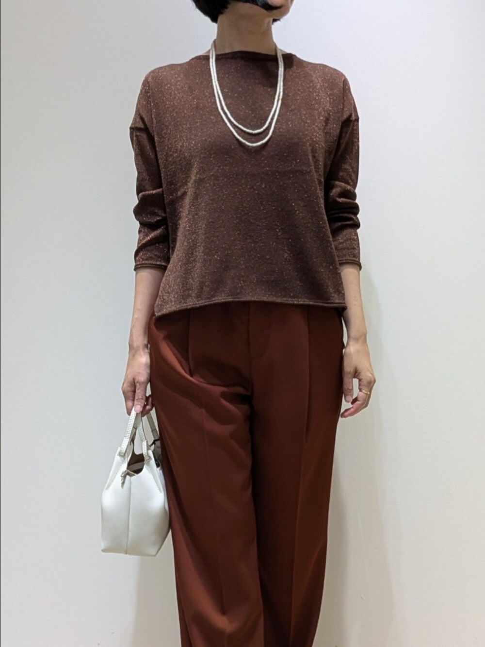 ブラウン系のその他パンツ、その他のニット/セーター、ホワイト系のネックレスを着用したレディースの秋コーディネートの2枚目の写真