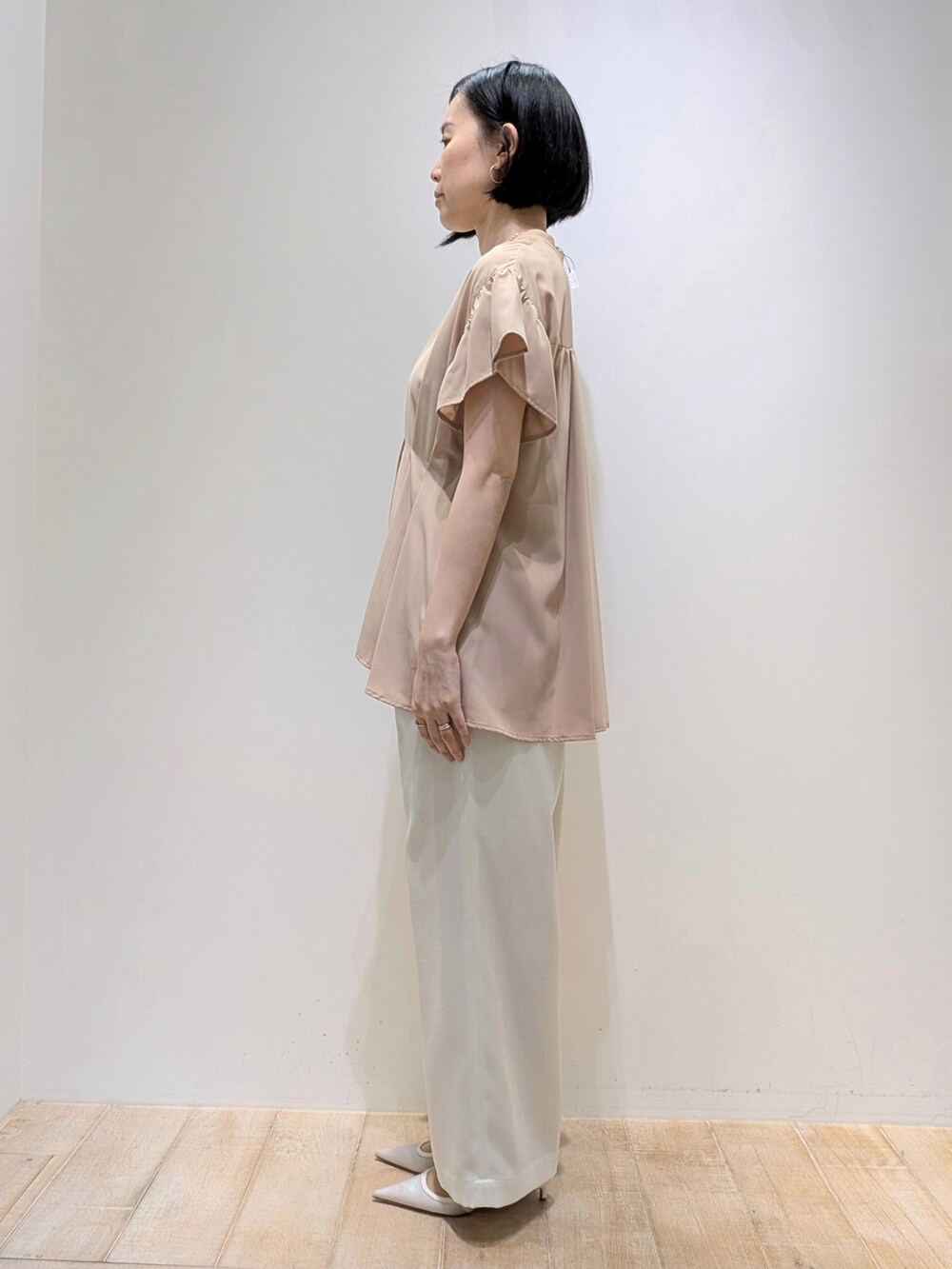 ホワイト系のスラックス、ベージュ系のシャツ/ブラウスを着用したレディースの夏コーディネートの3枚目の写真