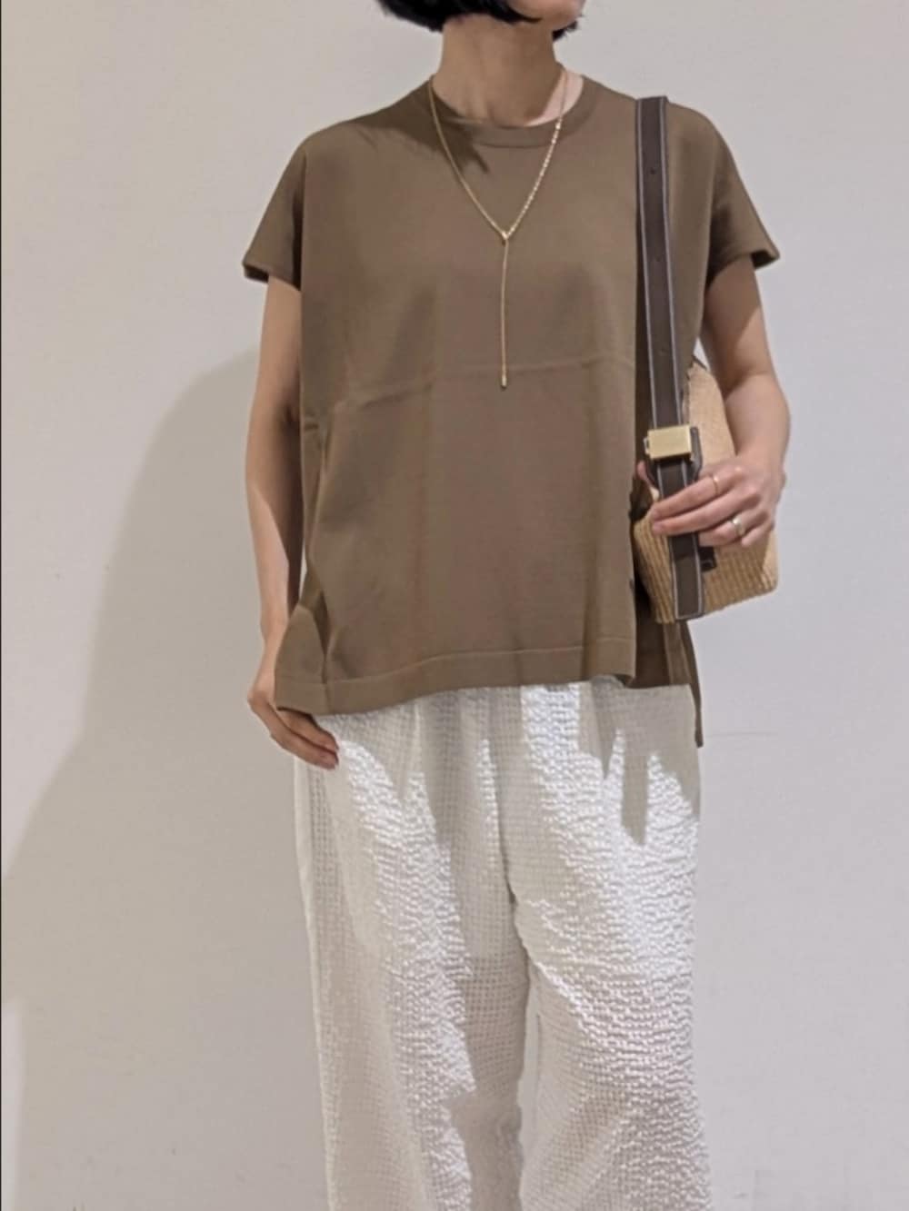 グレー系のニット/セーター、ホワイト系のその他パンツ、ゴールド系のネックレスを着用したレディースの夏コーディネートの2枚目の写真