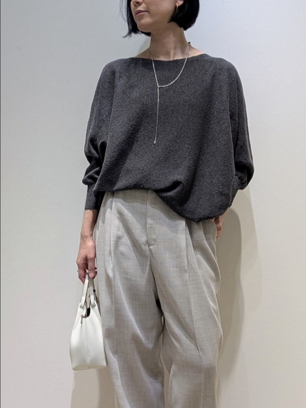 グレー系のニット/セーター、ベージュ系のその他パンツ、シルバー系のネックレスを着用したレディースの春コーディネートの2枚目の写真