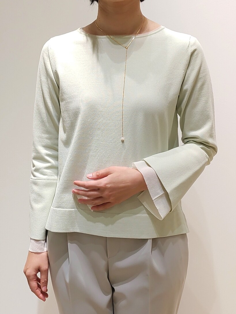 グリーン系のニット/セーター、ベージュ系のスラックスを着用したレディースの冬コーディネートの2枚目の写真