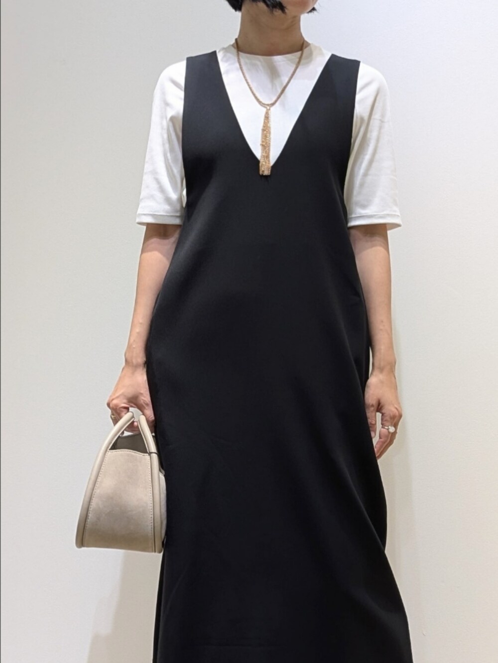 ホワイト系のTシャツ/カットソー、ブラック系のワンピース、ゴールド系のネックレスを着用したレディースの秋コーディネートの2枚目の写真