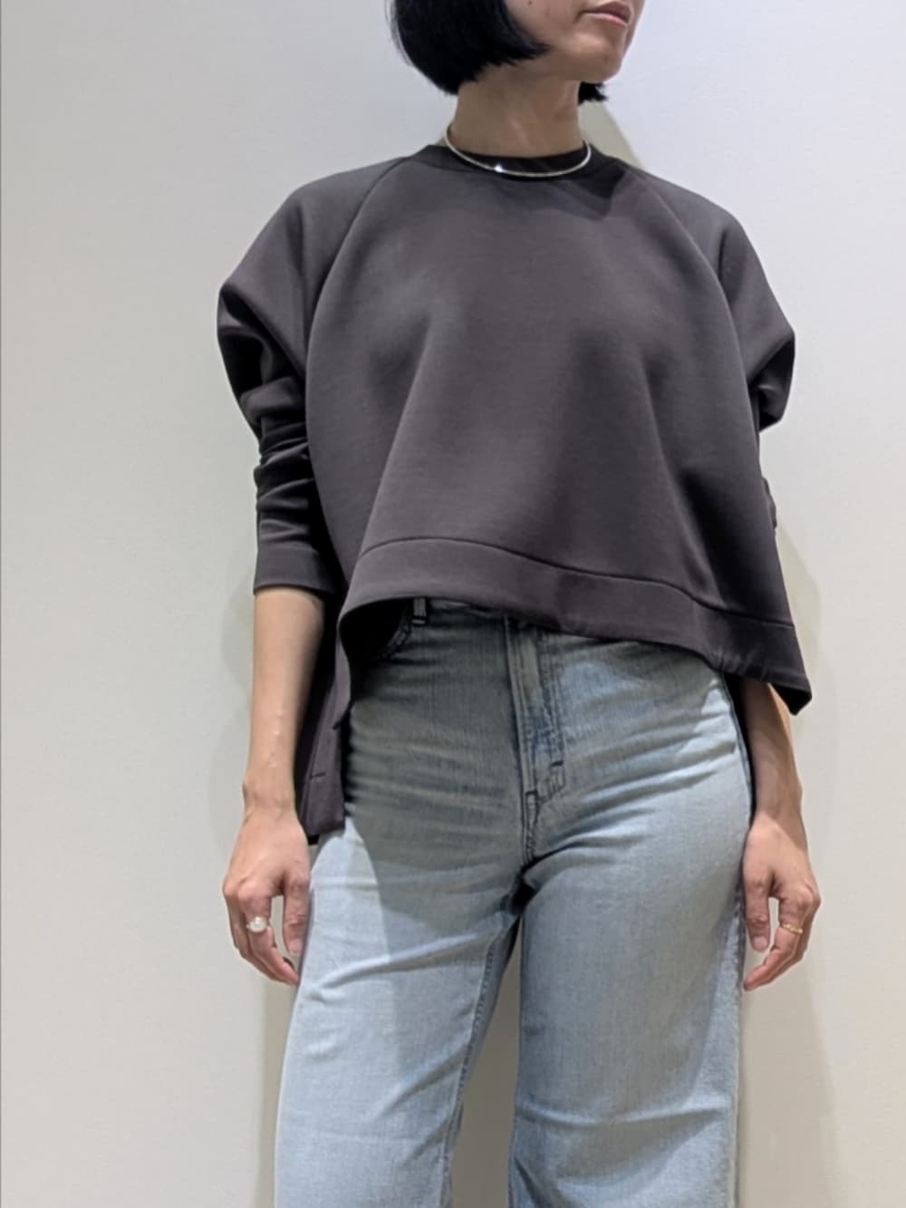 グレー系のスウェット、ブルー系のデニムパンツ、シルバー系のネックレスを着用したレディースの冬コーディネートの2枚目の写真