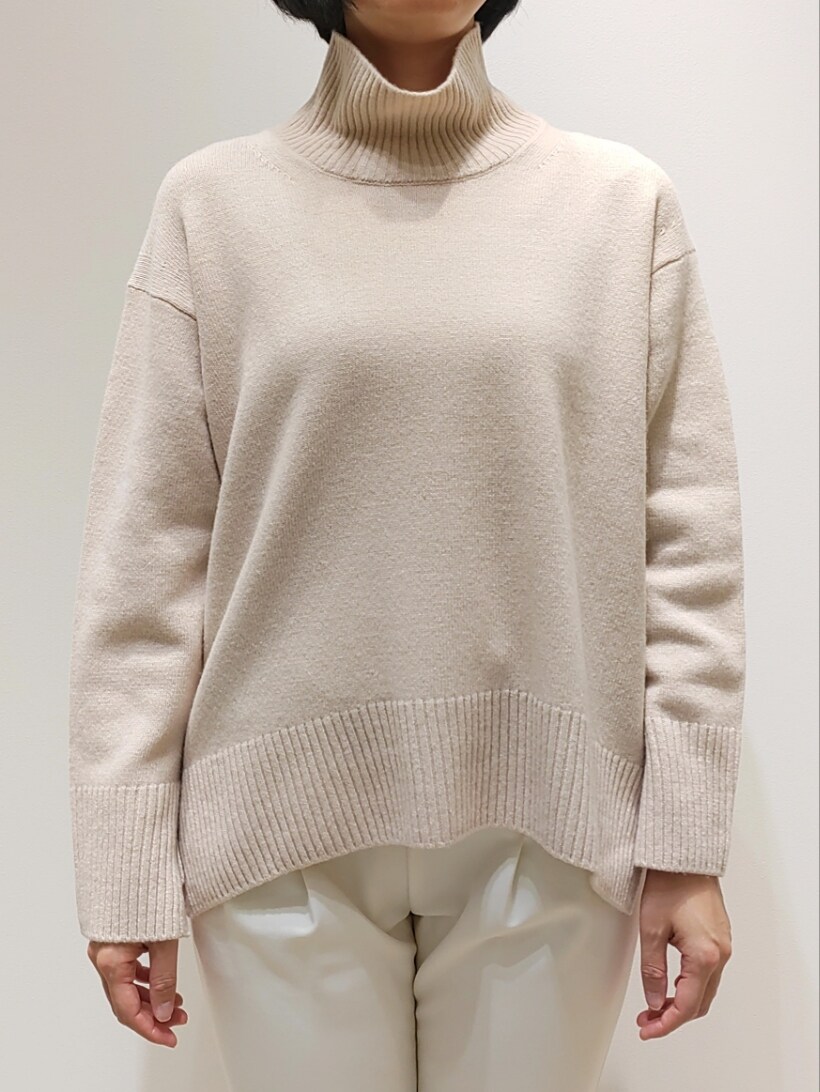 ベージュ系のニット/セーター、ホワイト系のスラックスを着用したレディースの冬コーディネートの2枚目の写真