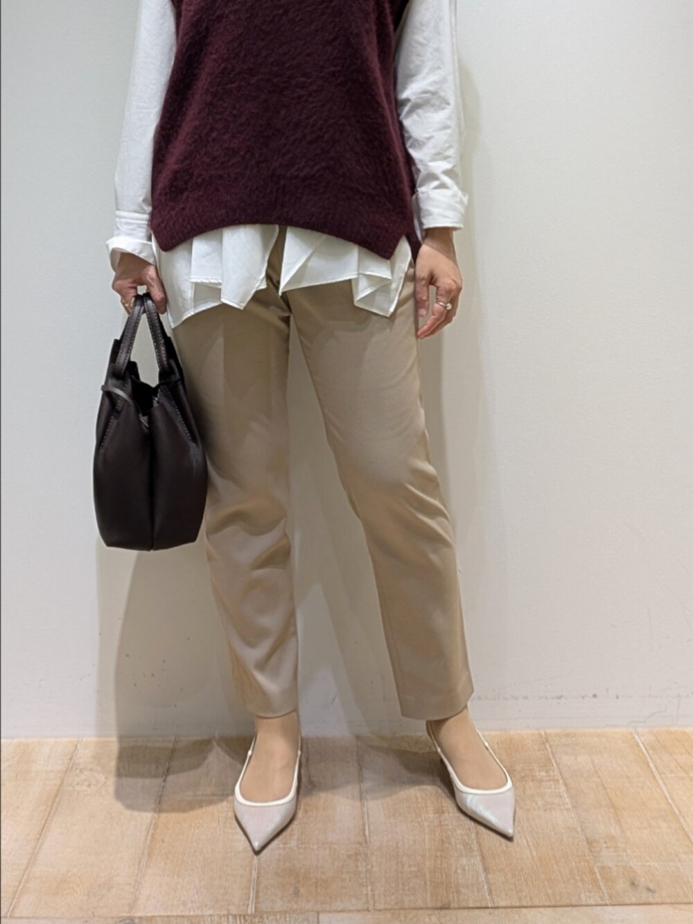 レッド系のベスト、ホワイト系のシャツ/ブラウス、ベージュ系のその他パンツを着用したレディースの秋コーディネートの3枚目の写真