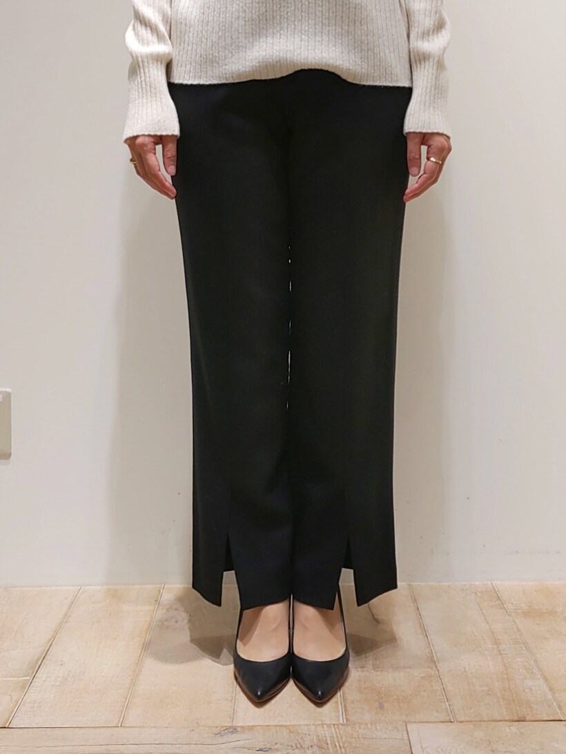 イエロー系のノーカラーコート、ブラック系のその他パンツ、ホワイト系のニット/セーターを着用したレディースの冬コーディネートの2枚目の写真