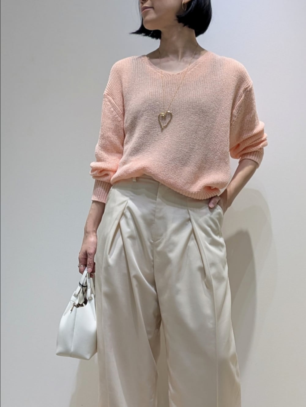 ピンク系のニット/セーター、ホワイト系のその他パンツを着用したレディースの春コーディネートの2枚目の写真