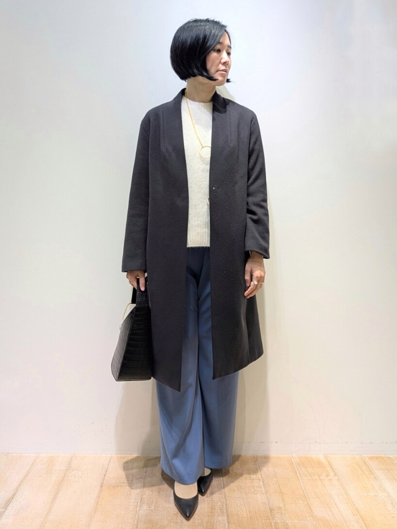 グレー系のチェスターコート、ブルー系のスラックス、ホワイト系のニット/セーターを着用したレディースの冬コーディネートの4枚目の写真