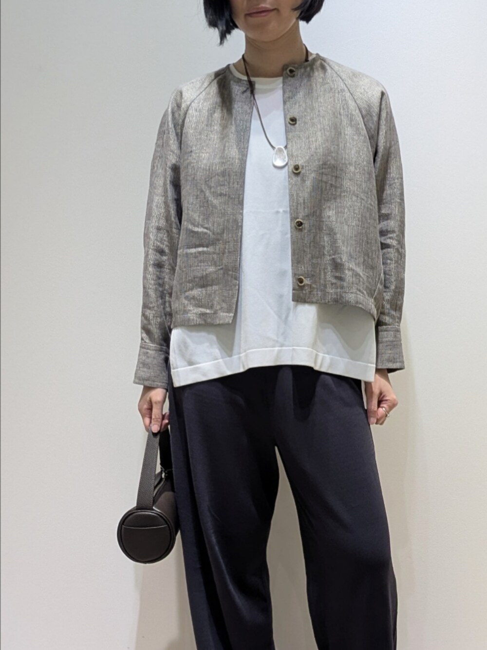 ベージュ系のブルゾン、グレー系のその他パンツ、ホワイト系のニット/セーターを着用したレディースの春コーディネートの2枚目の写真