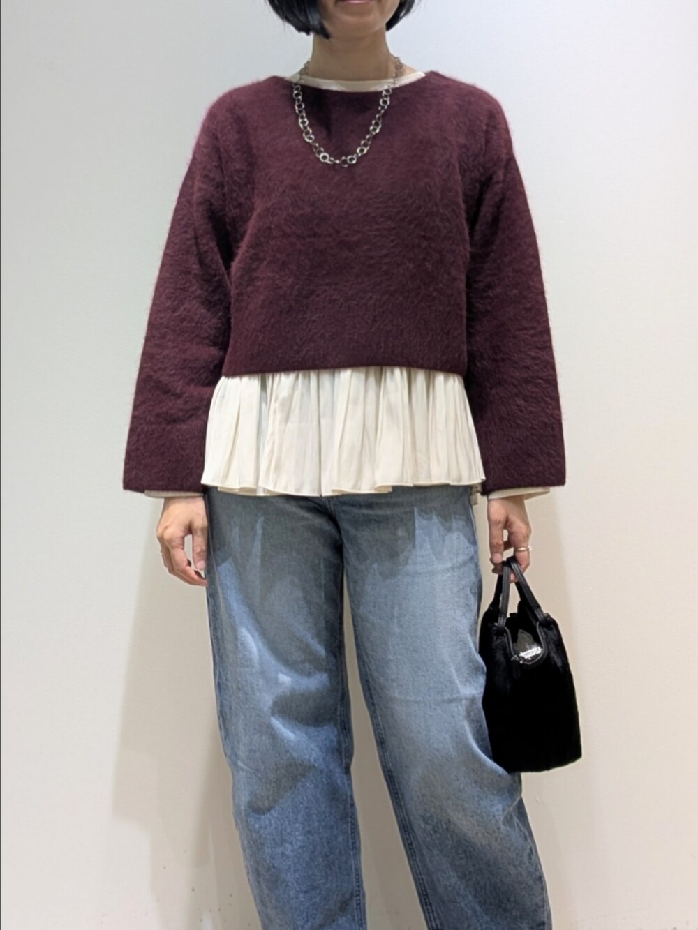 レッド系のニット/セーター、ホワイト系のシャツ/ブラウスを着用したレディースの冬コーディネートの2枚目の写真