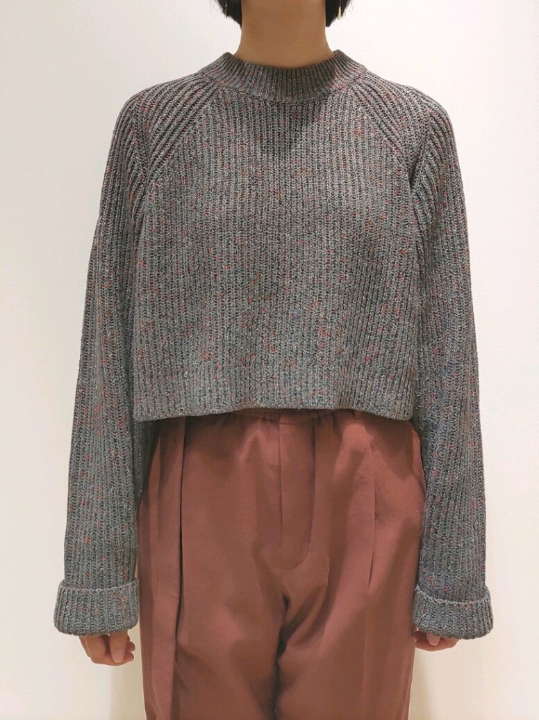 グレー系のニット/セーター、レッド系のスラックスを着用したレディースの秋コーディネートの2枚目の写真