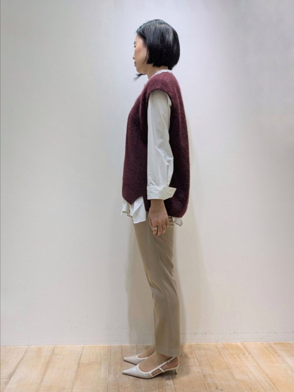 レッド系のベスト、ホワイト系のシャツ/ブラウス、ベージュ系のその他パンツを着用したレディースの秋コーディネートの4枚目の写真