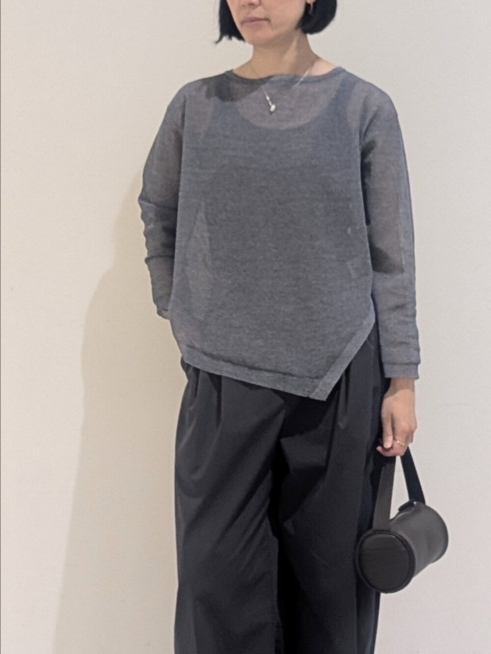 ブルー系のニット/セーター、グレー系のその他パンツ、シルバー系のネックレスを着用したレディースの夏コーディネートの2枚目の写真