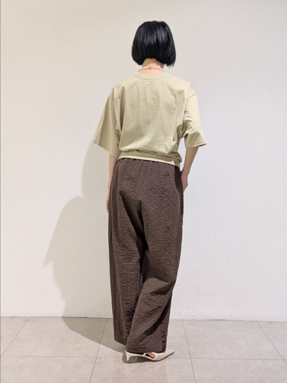 グリーン系のTシャツ/カットソー、ブラウン系のその他パンツ、ホワイト系のネックレスを着用したレディースの夏コーディネートの5枚目の写真