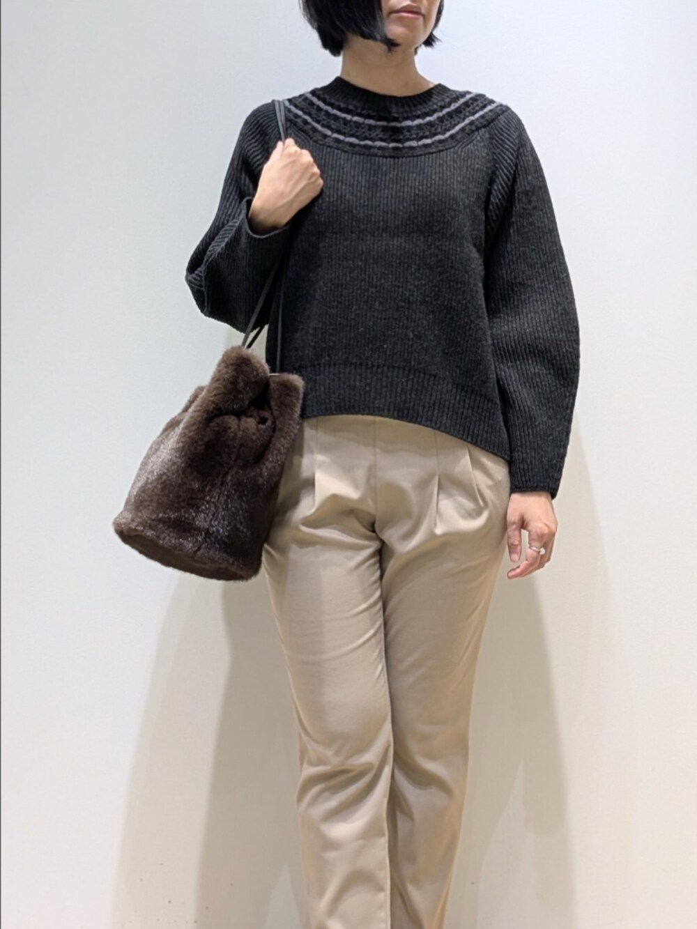 グレー系のニット/セーター、ベージュ系のその他パンツ、ブラウン系のショルダーバッグを着用したレディースの秋コーディネートの2枚目の写真