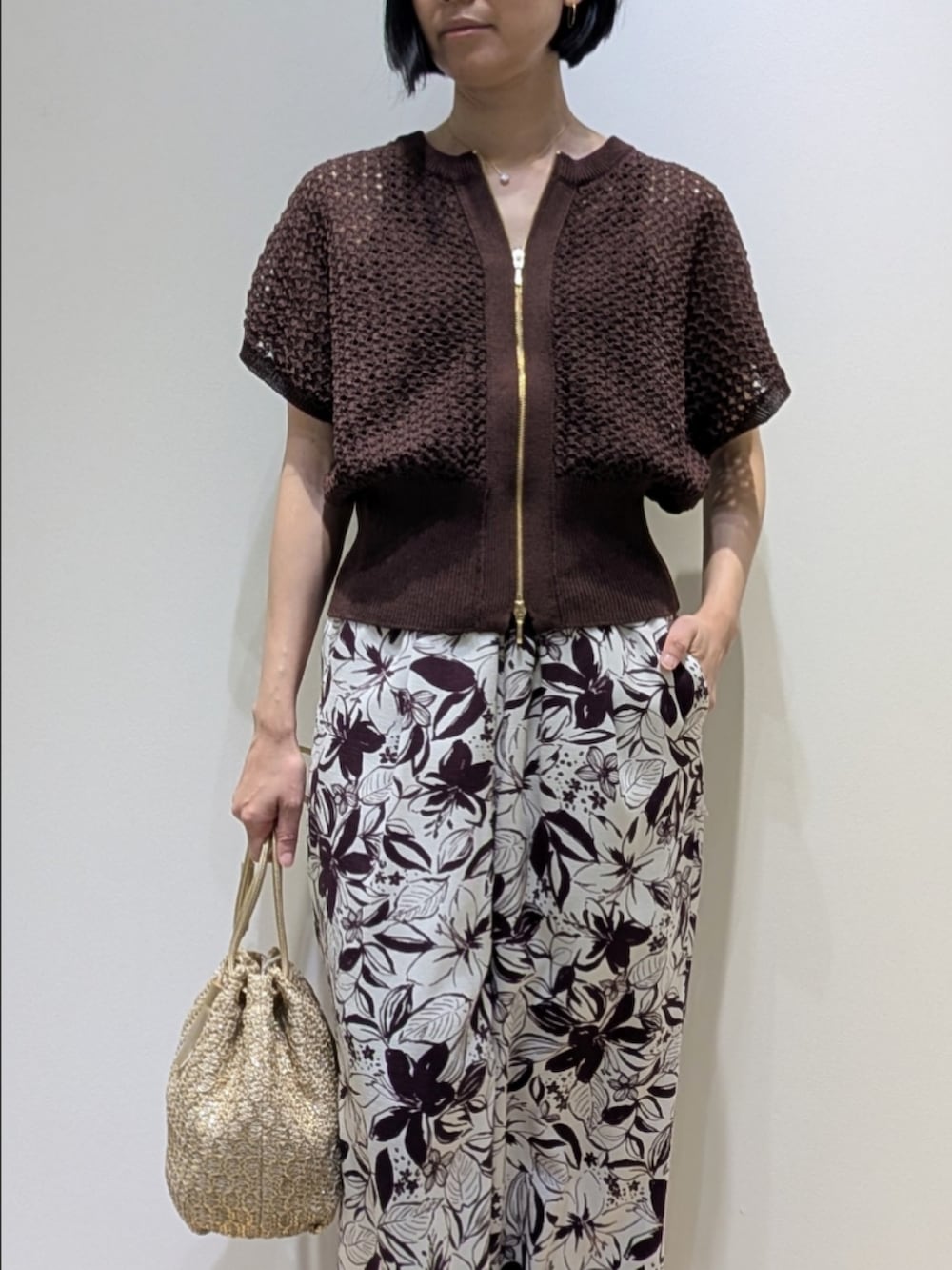 ブラウン系のニット/セーター、レッド系のその他パンツ、ゴールド系のショルダーバッグを着用したレディースの春コーディネートの2枚目の写真