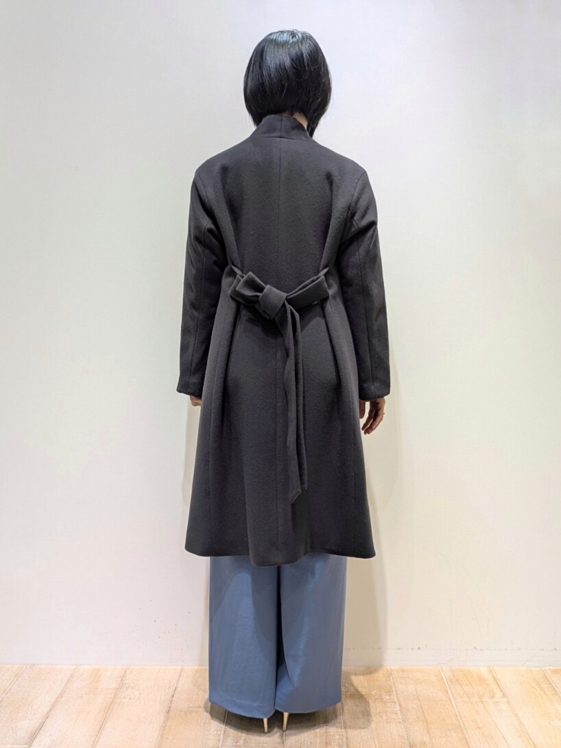 グレー系のチェスターコート、ブルー系のスラックス、ホワイト系のニット/セーターを着用したレディースの冬コーディネートの3枚目の写真