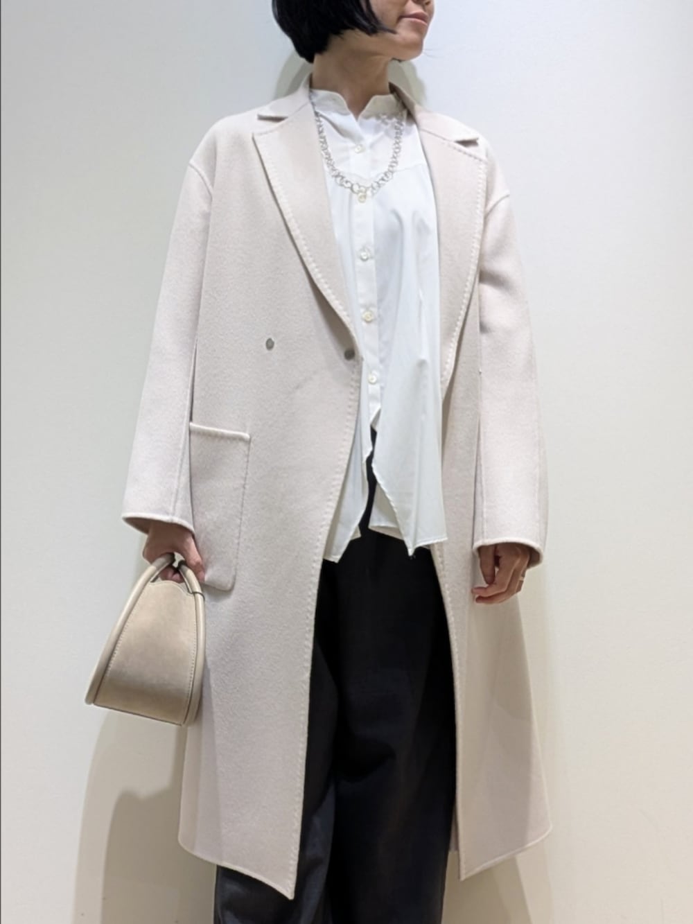 ベージュ系のチェスターコート、ホワイト系のシャツ/ブラウス、グレー系のその他パンツを着用したレディースの秋コーディネートの2枚目の写真