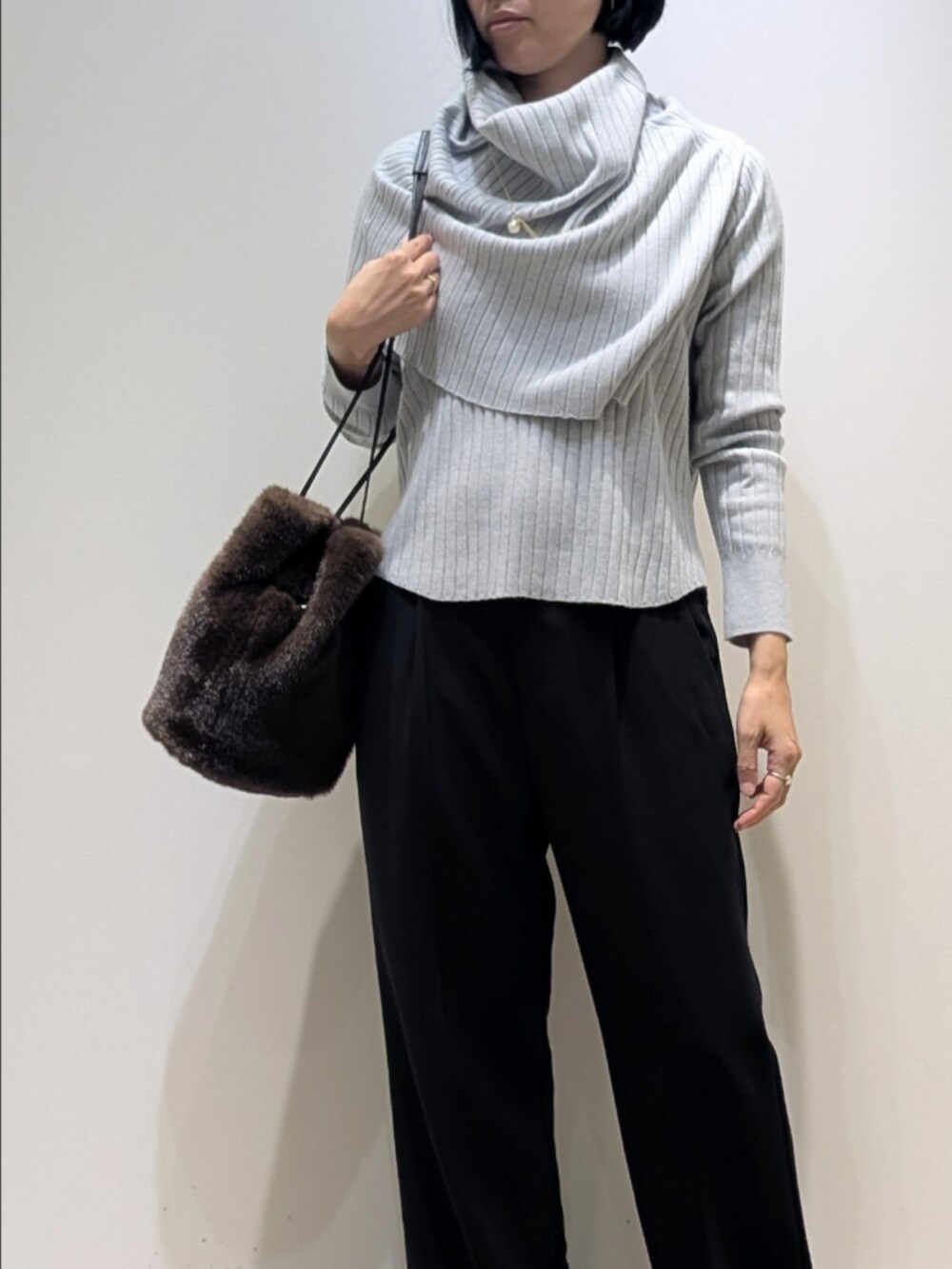 ブルー系のニット/セーター、ブラック系のその他パンツ、ブラウン系のショルダーバッグを着用したレディースの冬コーディネートの2枚目の写真