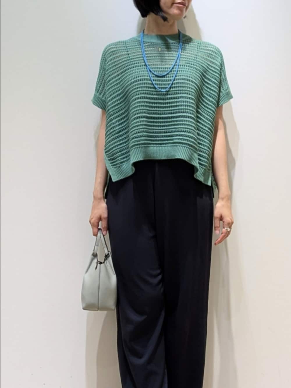 グリーン系のニット/セーター、グレー系のその他パンツを着用したレディースの夏コーディネートの2枚目の写真
