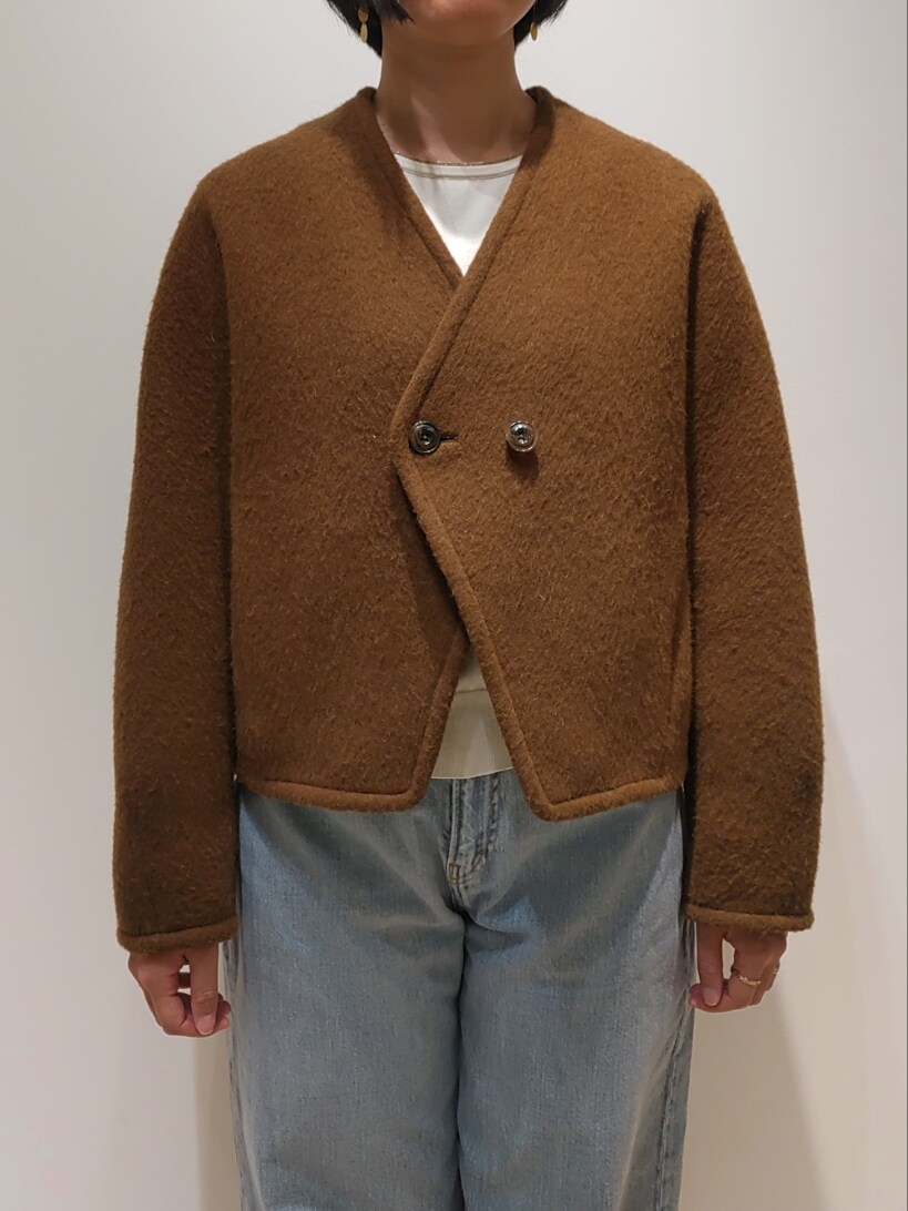 イエロー系のノーカラーコート、ホワイト系のニット/セーター、ブルー系のデニムパンツを着用したレディースの冬コーディネートの2枚目の写真