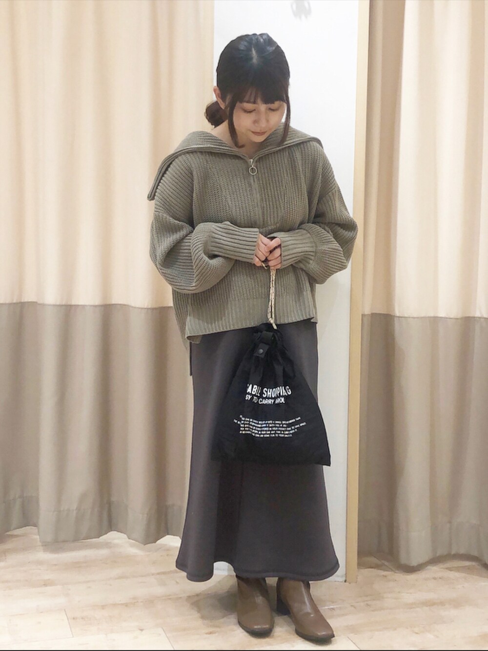 ブラウン系のニット/セーター、グレー系のスカート、ブラック系のエコバッグ/サブバッグを着用したレディースの秋コーディネートの2枚目の写真